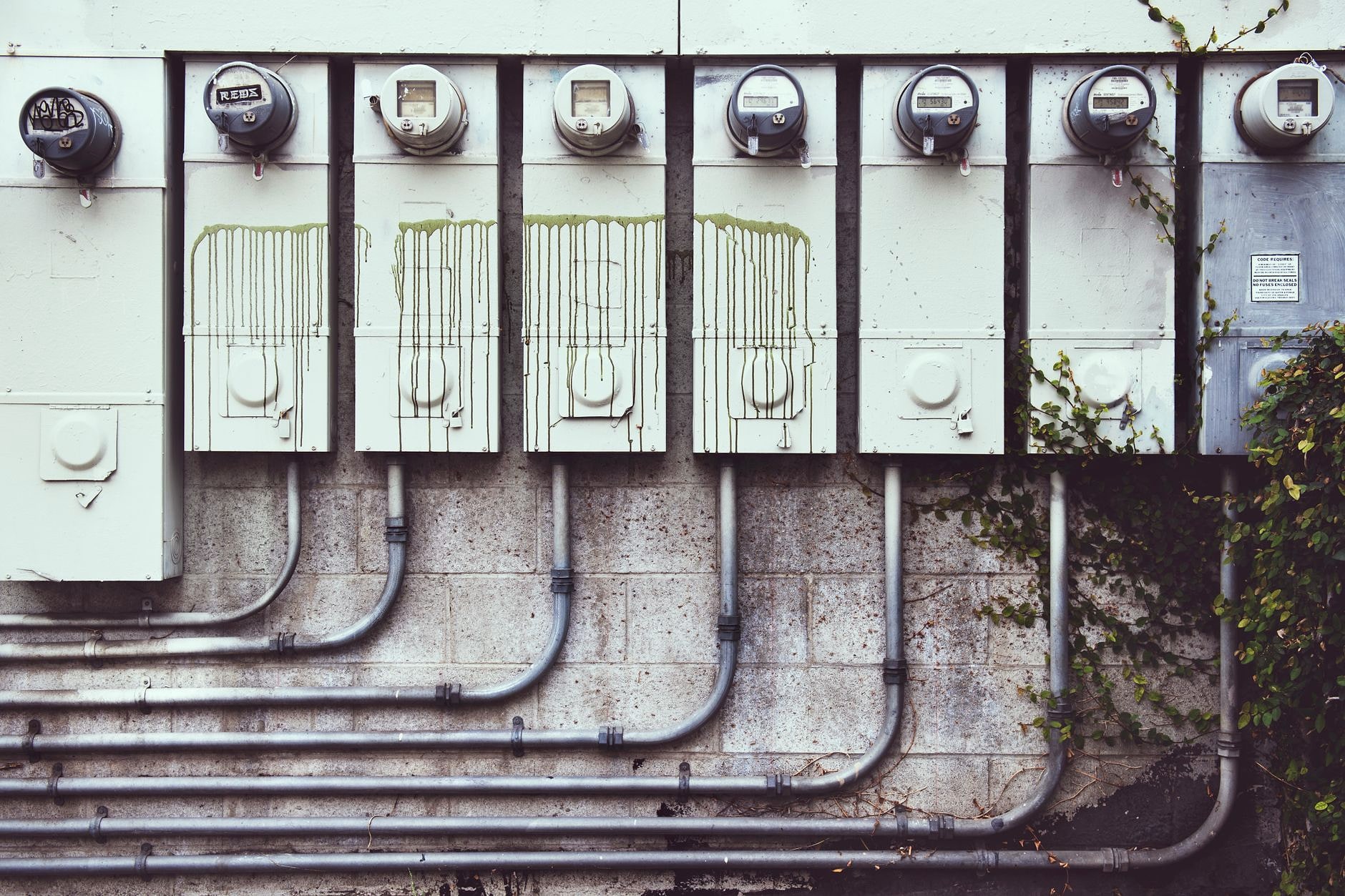 Row of outdoor electric meters with conduit on a brick wall